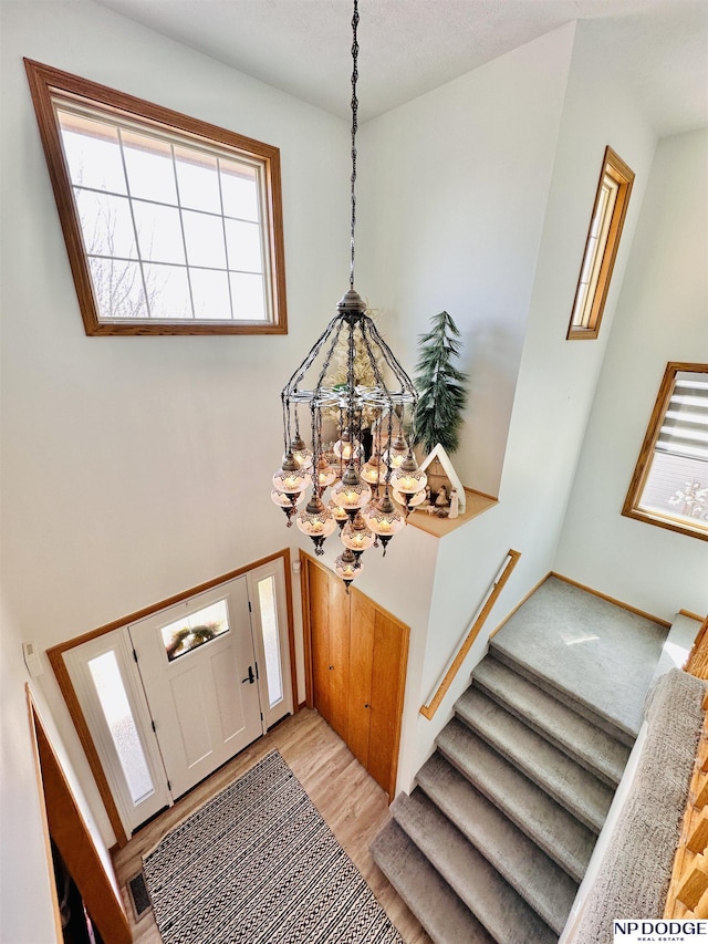 entrance foyer featuring a chandelier, baseboards, light wood-style flooring, and stairway