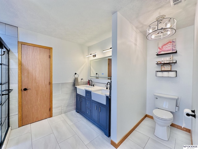 full bathroom featuring a textured ceiling, tile patterned flooring, toilet, a sink, and double vanity