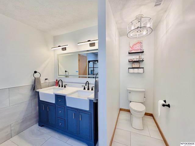 bathroom featuring a sink, tile patterned floors, a textured ceiling, and toilet