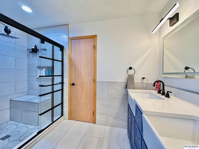 bathroom with a tile shower, tile walls, recessed lighting, vanity, and tile patterned floors