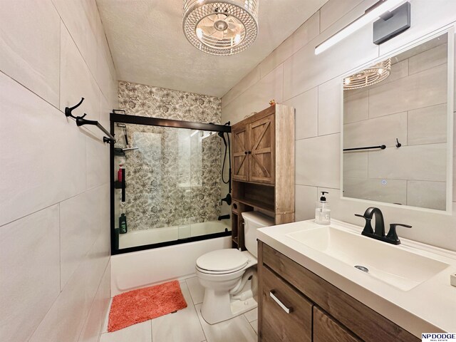 full bathroom featuring bath / shower combo with glass door, vanity, toilet, tile walls, and tile patterned floors