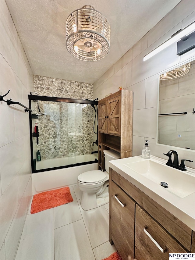 full bathroom featuring toilet, tile walls, vanity, and bath / shower combo with glass door