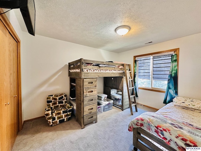 carpeted bedroom featuring visible vents, baseboards, and a textured ceiling