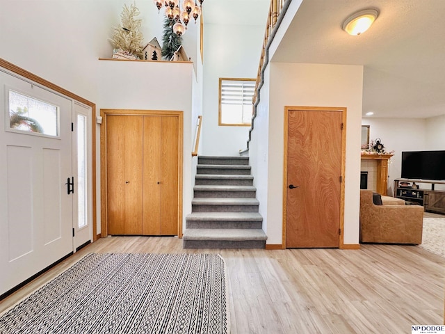 entrance foyer featuring wood finished floors, a tiled fireplace, baseboards, and stairs