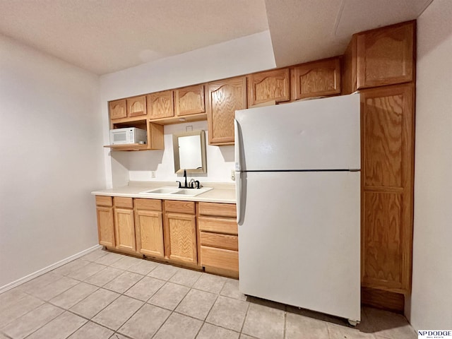 kitchen with baseboards, white appliances, light countertops, light tile patterned flooring, and a sink