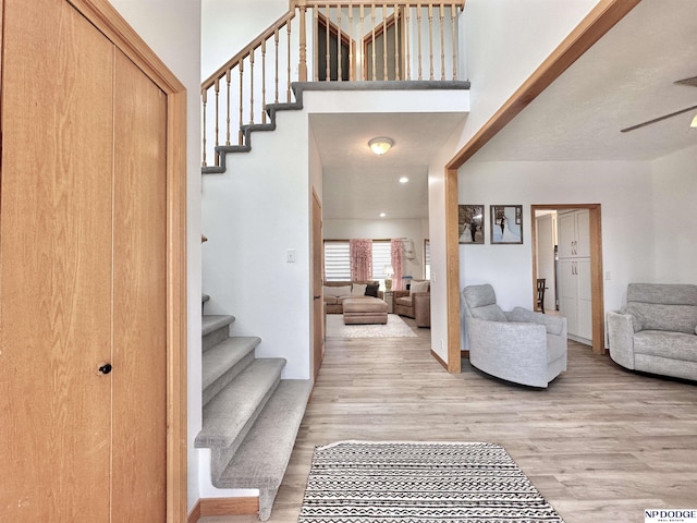 foyer with stairs, a ceiling fan, and wood finished floors