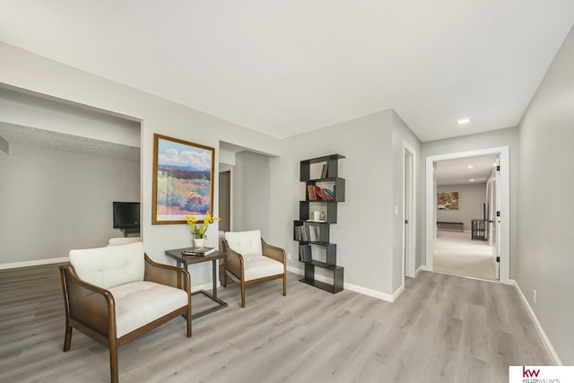 sitting room featuring baseboards, recessed lighting, and light wood-style flooring