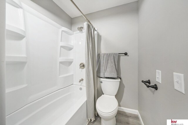bathroom with toilet, baseboards, wood finished floors, and shower / tub combo with curtain
