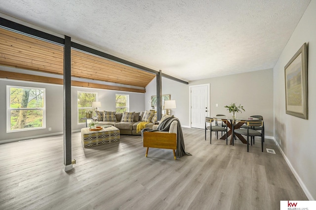 living room featuring baseboards, a textured ceiling, wood finished floors, and visible vents