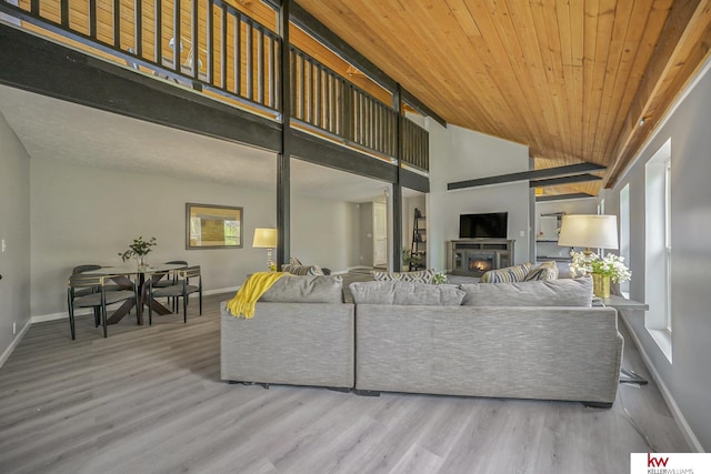 living area with baseboards, a glass covered fireplace, and wood finished floors