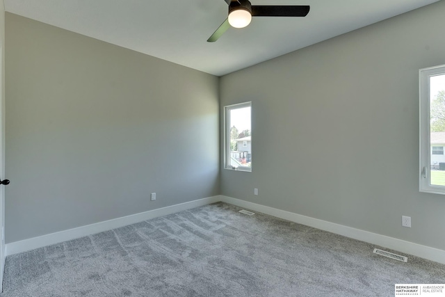 carpeted spare room featuring visible vents, baseboards, and ceiling fan