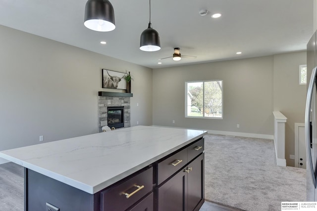 kitchen featuring a wealth of natural light, a ceiling fan, a stone fireplace, and open floor plan