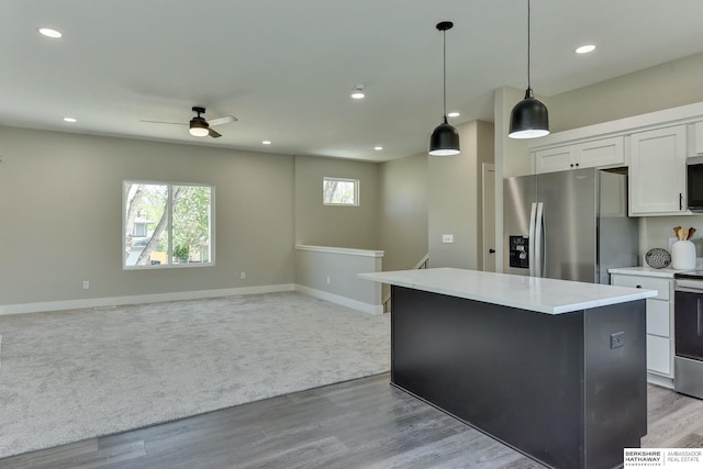 kitchen featuring stainless steel fridge, baseboards, a kitchen island, and white cabinetry