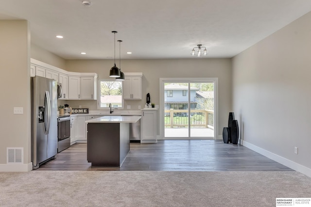 kitchen featuring visible vents, open floor plan, a sink, carpet, and appliances with stainless steel finishes