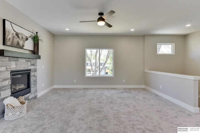 unfurnished living room with recessed lighting, a ceiling fan, carpet flooring, and a stone fireplace