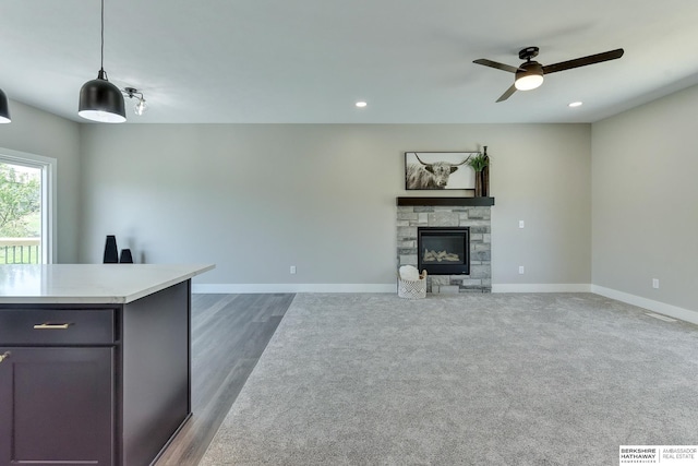 unfurnished living room featuring a stone fireplace, baseboards, dark wood-type flooring, recessed lighting, and a ceiling fan
