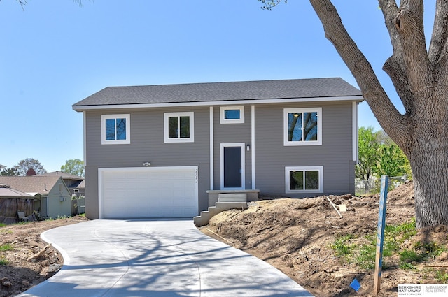 bi-level home with a garage, entry steps, and concrete driveway