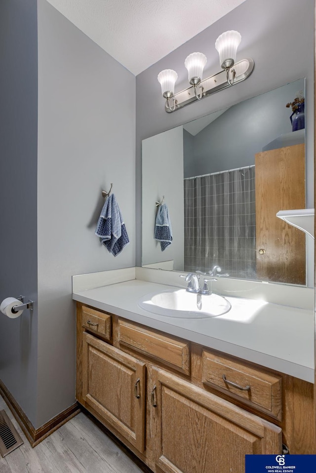 full bathroom featuring visible vents, vanity, wood finished floors, baseboards, and a shower with curtain