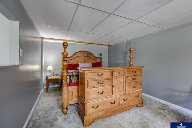 bedroom featuring baseboards, a drop ceiling, and light colored carpet