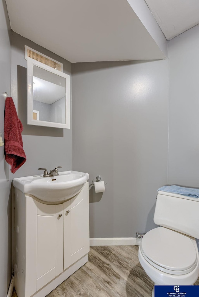 bathroom featuring toilet, baseboards, wood finished floors, and vanity