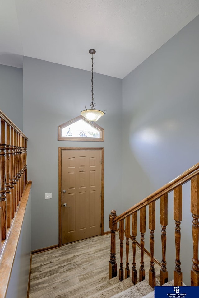 foyer entrance featuring stairs, baseboards, and light wood-style floors