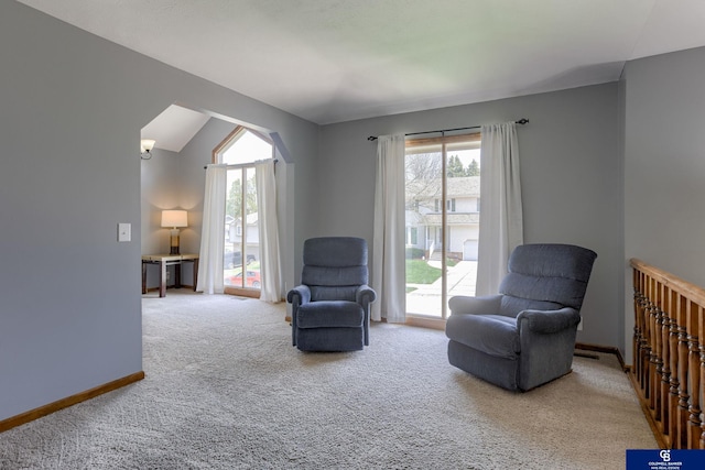living area with baseboards, lofted ceiling, and carpet