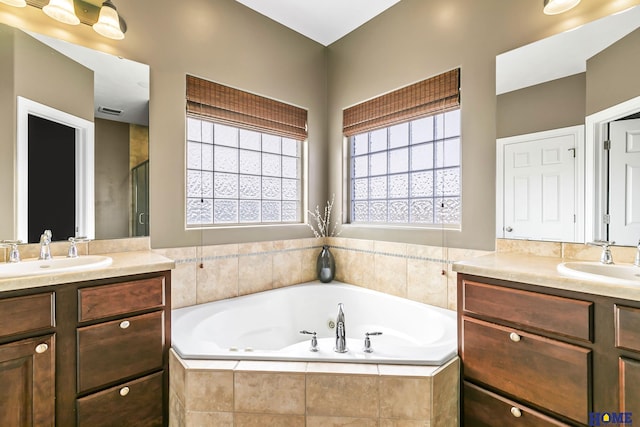 full bathroom with a sink, a whirlpool tub, two vanities, and a stall shower