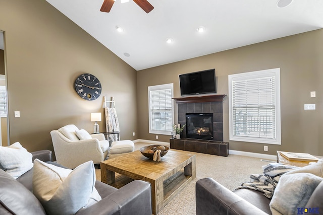 carpeted living room featuring a tile fireplace, baseboards, a ceiling fan, and vaulted ceiling