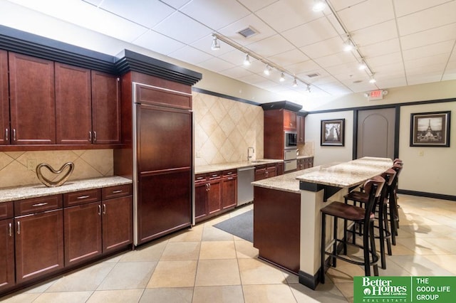 210 S 16th St Unit 901, Omaha, NE 68102 - kitchen with rail lighting, built in appliances, a kitchen island, a breakfast bar area, and light stone counters