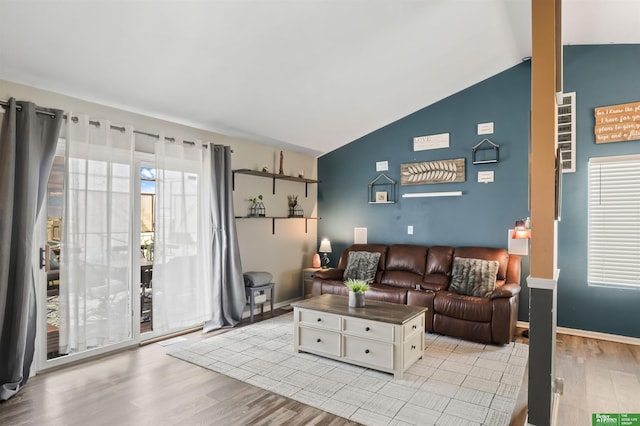 living room featuring light wood-type flooring, baseboards, and lofted ceiling