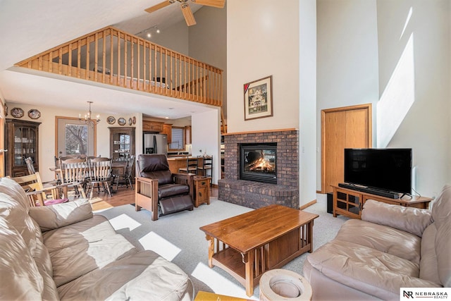 living room with light carpet, ceiling fan with notable chandelier, high vaulted ceiling, and a fireplace