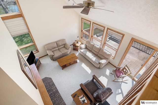 living room featuring carpet, baseboards, a ceiling fan, and lofted ceiling