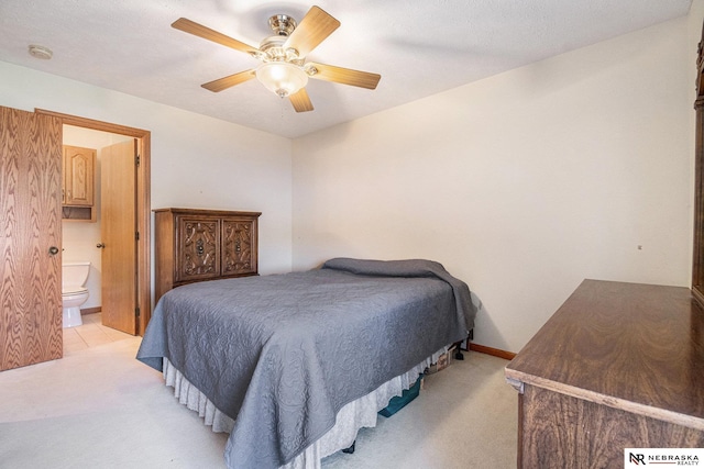 bedroom featuring ensuite bath, light colored carpet, and ceiling fan