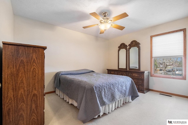 bedroom featuring light carpet, visible vents, baseboards, and a ceiling fan