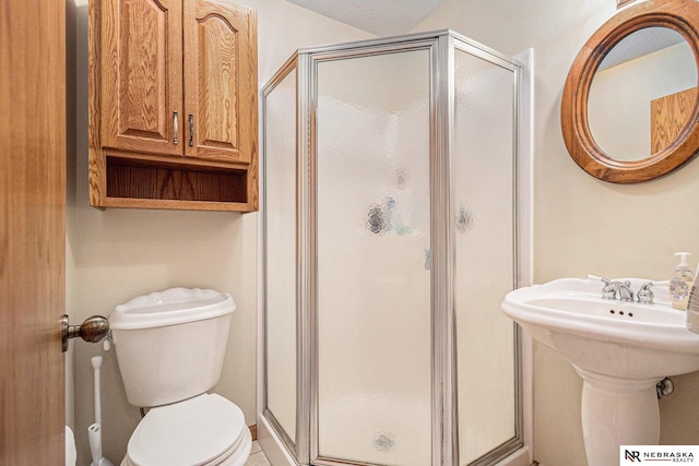 full bath featuring a shower stall, a sink, and toilet