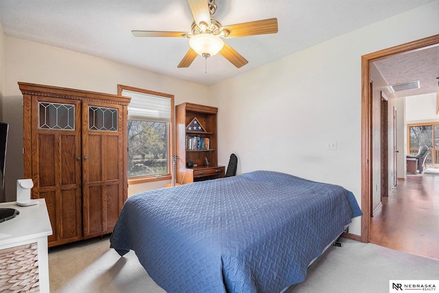 bedroom with baseboards, light colored carpet, ceiling fan, and visible vents