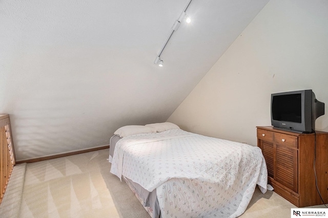 bedroom featuring rail lighting and light colored carpet