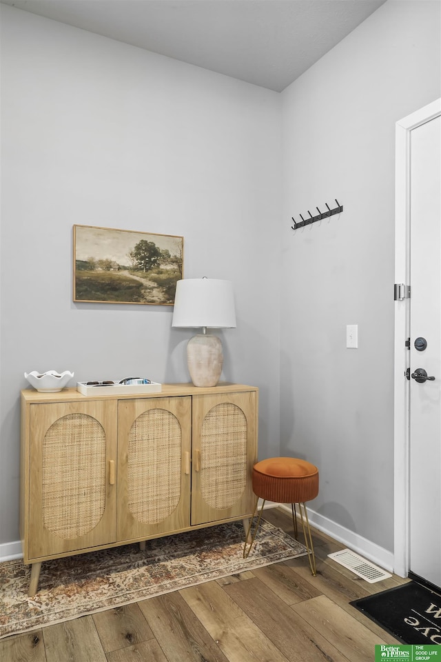 living area featuring visible vents, baseboards, and wood finished floors