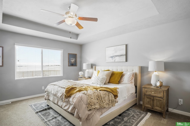 bedroom featuring carpet flooring, ceiling fan, baseboards, and a raised ceiling