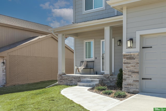property entrance featuring a yard, stone siding, covered porch, and a garage