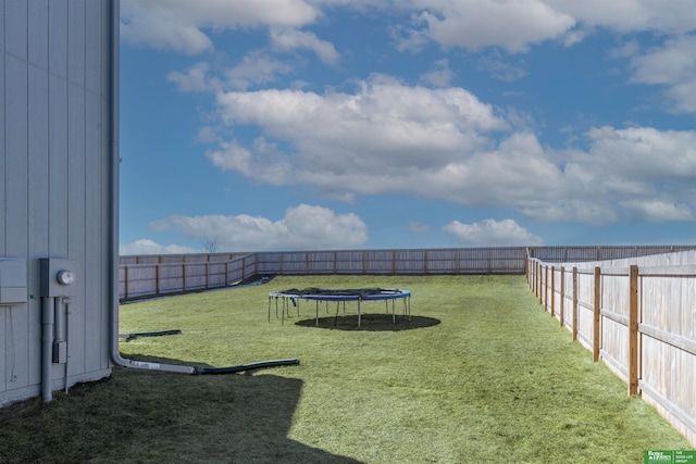 view of yard featuring a trampoline and a fenced backyard
