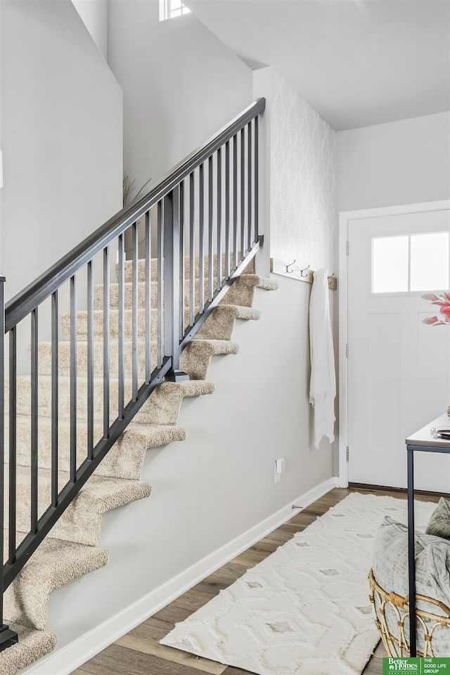 foyer featuring baseboards, stairway, and wood finished floors