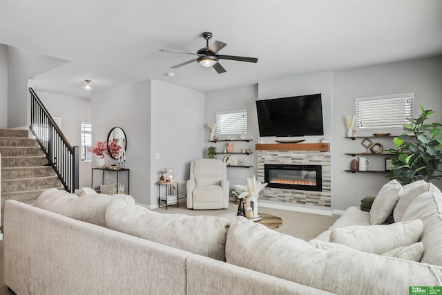 carpeted living area featuring a tiled fireplace, stairway, baseboards, and ceiling fan