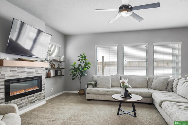living room featuring a fireplace, light colored carpet, baseboards, and a ceiling fan