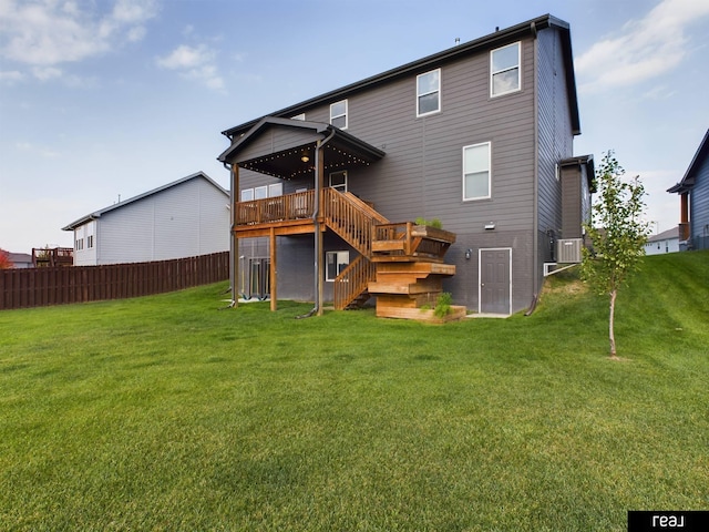 rear view of house with a yard, fence, a wooden deck, and stairs