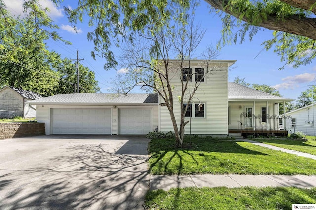 traditional home featuring driveway, a garage, a front yard, covered porch, and roof with shingles