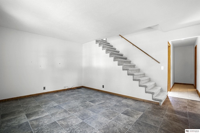 interior space featuring baseboards, stairs, and dark stone finish floors