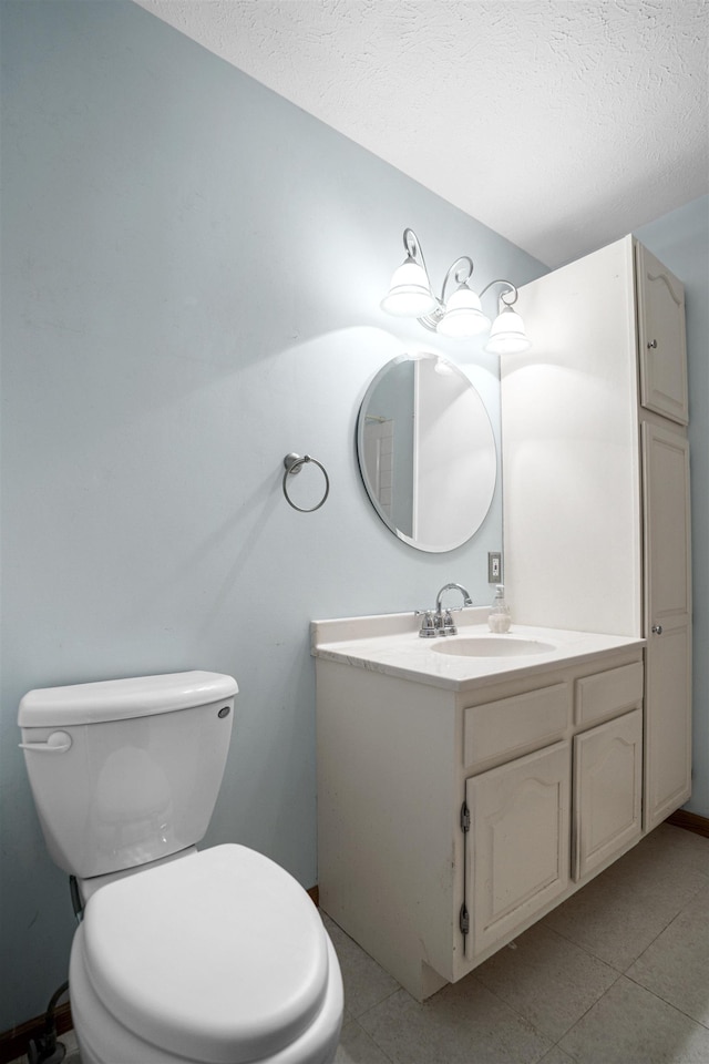 half bath with a textured ceiling, tile patterned flooring, toilet, and vanity