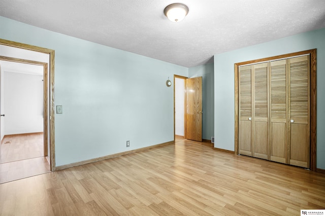 unfurnished bedroom featuring light wood-style flooring, a closet, a textured ceiling, and baseboards