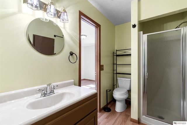 bathroom with wood finished floors, a shower stall, vanity, and toilet